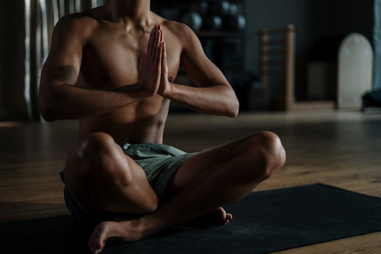 gallery-4 A young man meditates in a yoga studio, promoting relaxation and wellness.